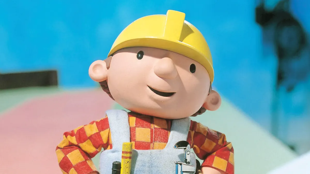 A still from the children's show Bob the Builder: a smiling stop-motion builder in a yellow hard hat and red checked shirt.